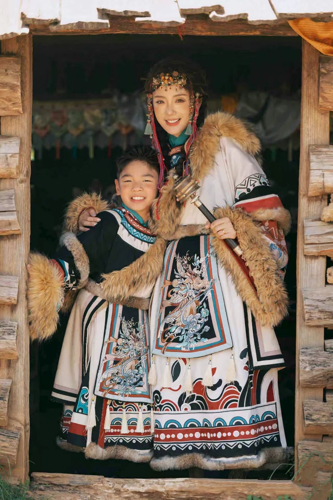 Two individuals in traditional embroidered clothing standing inside a wooden structure.