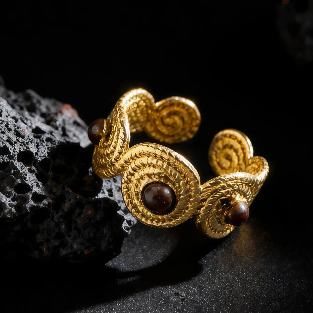 Angled view of a gold braided ring band set with round Tiger's Eye gemstones on a dark surface.