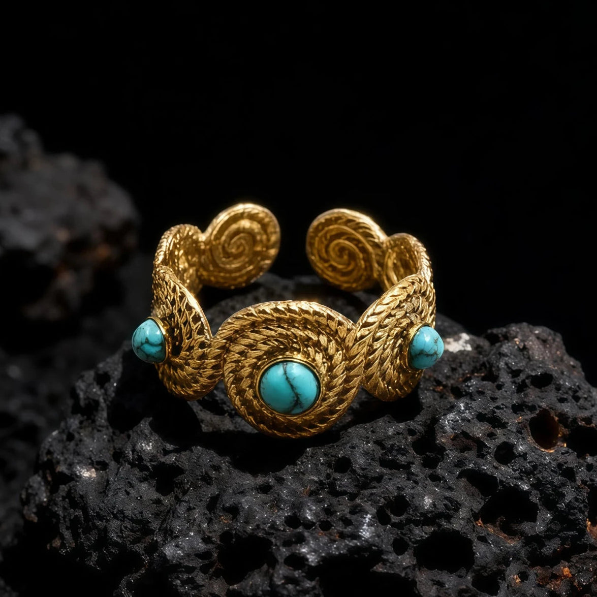 A gold-plated Tibetan ring with turquoise stones resting on black lava rock.