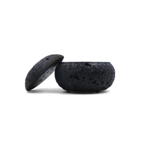Balance & Clarity Feng Shui Lunar Incense Burner, black round incense holder with moon-like textured porous surface and partially open lid revealing interior, spiritual home decor for meditation and balance on a clean white background.