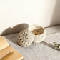 Textured ceramic candle holder with a small candle inside on a light surface.