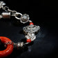 Tibetan Silver bracelet with red beads and charms on a black background