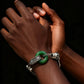 Close-up of a hand wearing a tibetan silver bracelet with a green stone on a dark background