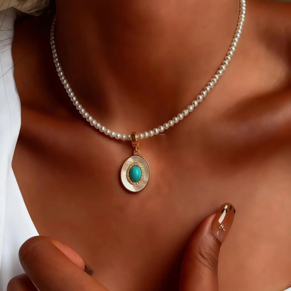 Pearl necklace with a turquoise pendant on a person's neck