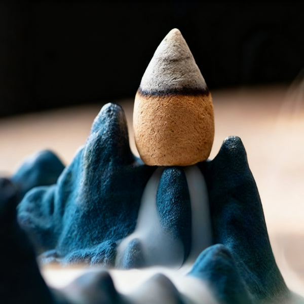 Close-up of Tibetan Backflow Incense Burner with Mountain Design, Showing Cone Incense and Flowing Smoke