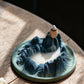 Tibetan Backflow Incense Burner on Wooden Table with Mountain Design and Flowing Smoke, Creating Tranquil Light and Shadow Scene