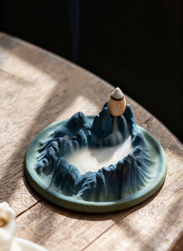 Tibetan Backflow Incense Burner on Wooden Table with Mountain Design and Flowing Smoke, Creating Tranquil Light and Shadow Scene