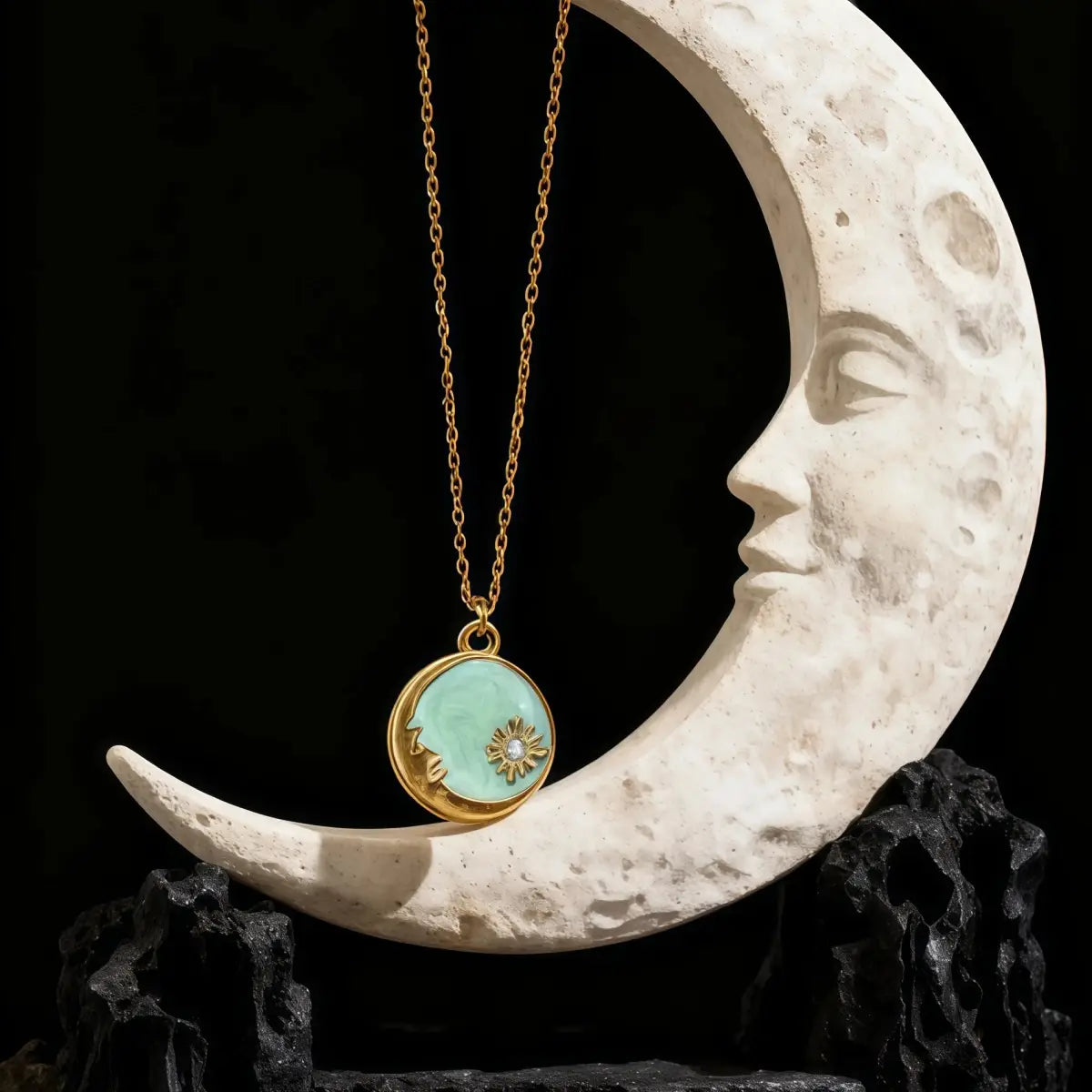 Necklace with a turquoise pendant hanging from a crescent moon sculpture on a dark background