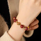 Close-up of a wrist wearing a red beaded bracelet with gold accents.