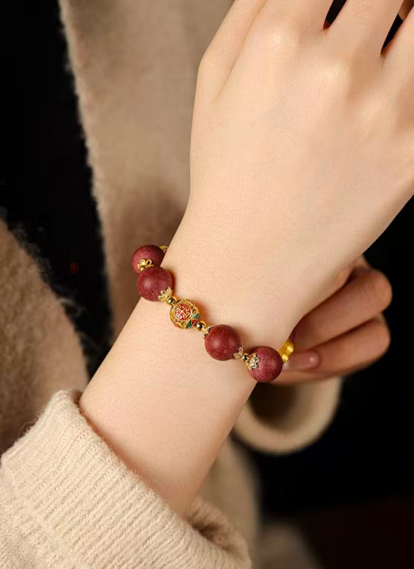 Close-up of a wrist wearing a red beaded bracelet with gold accents.