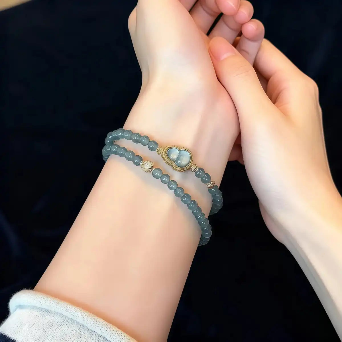 Blue jade beaded bracelet with heart charm worn on wrist, close-up view