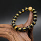 Black and gold Buddhist Mantra beaded bracelet on a wooden surface with a dark background
