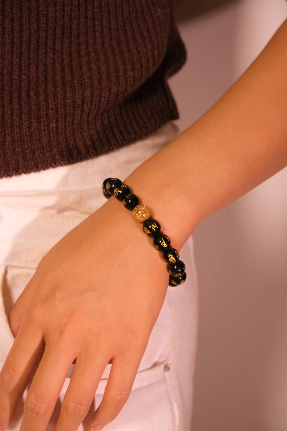 Black Buddhis Mantra beaded bracelet on a wrist with a blurred background