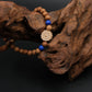 Buddhist Prayer Bracelet with wooden beads and a decorative flower charm on a dark background