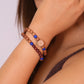 Close-up of a person wearing a buddhist prayer bracelet with beads on a plain background