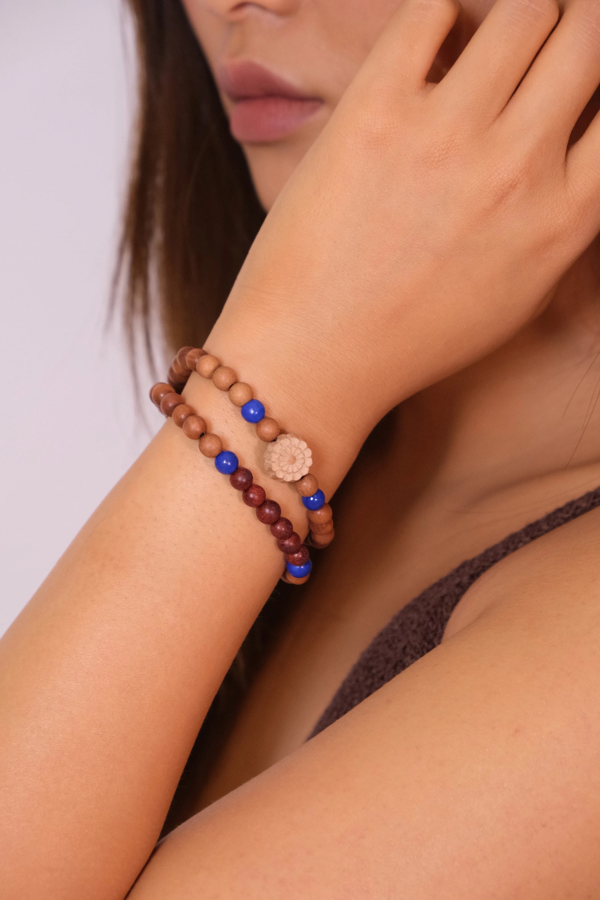 Close-up of a person wearing a buddhist prayer bracelet with beads on a plain background