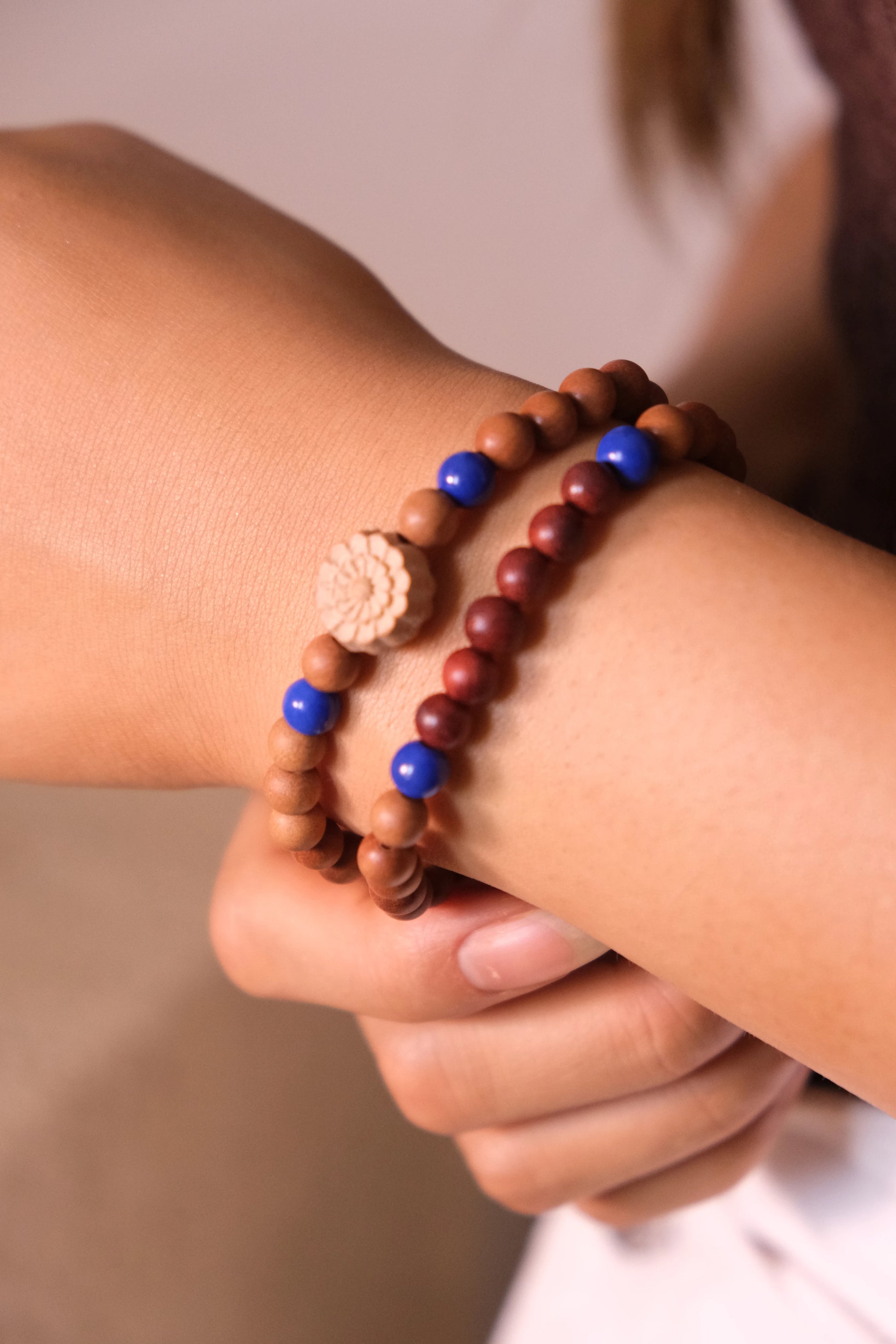 Close-up of a wrist wearing multi-cycle Buddhist Prayer beaded bracelets with blue and brown beads.