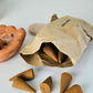 Incense cones spilling out of a brown paper bag on a white surface
