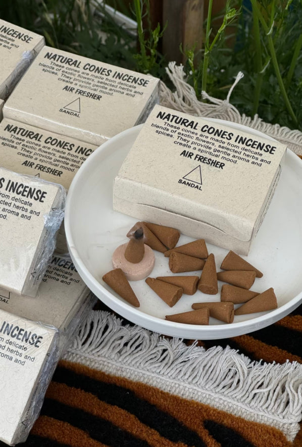Sandalwood natural cone incense on a white plate with packaging in the background.