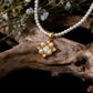 Pearl necklace with a gold pendant on a wooden branch with flowers