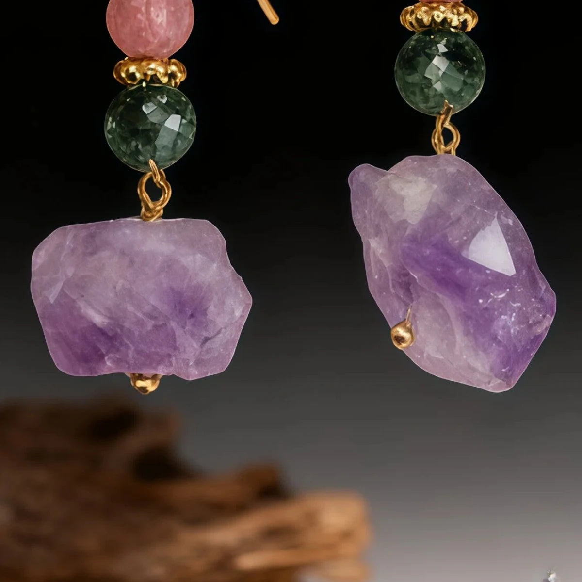 Earrings with purple and green gemstones on a dark background