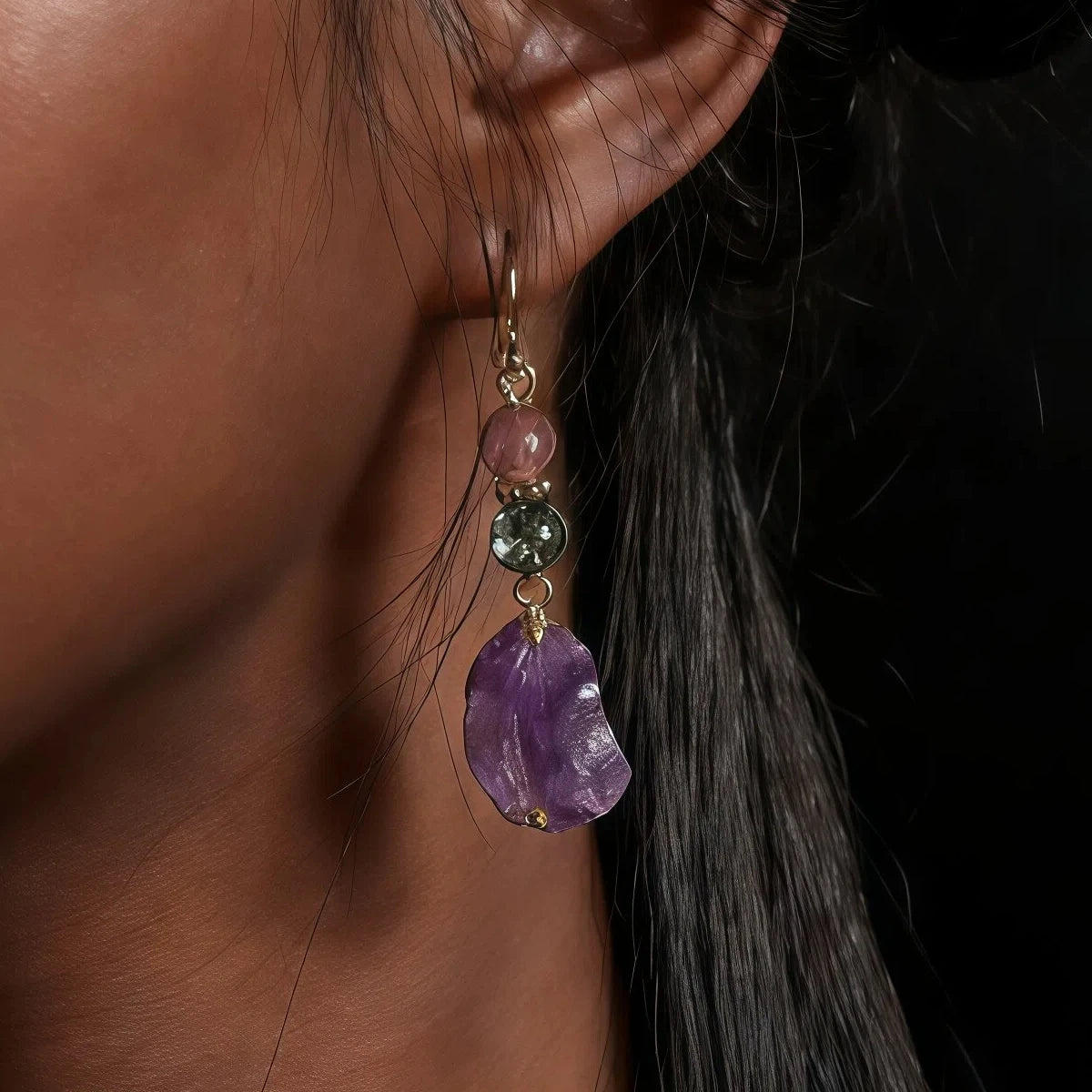 Close-up of an earring with a purple gemstone on a dark background