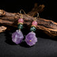 Earrings with purple and green gemstones on a dark background