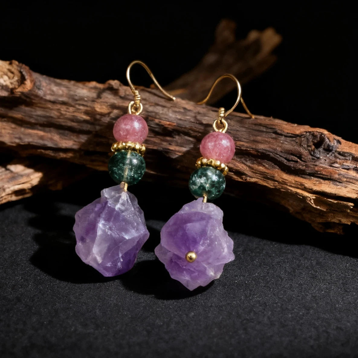 Earrings with purple and green gemstones on a dark background
