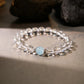 Bracelet with clear beads and a blue gemstone on a neutral background