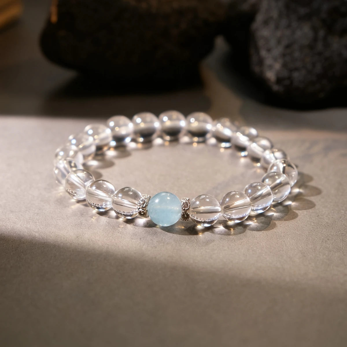 Bracelet with clear beads and a blue gemstone on a neutral background