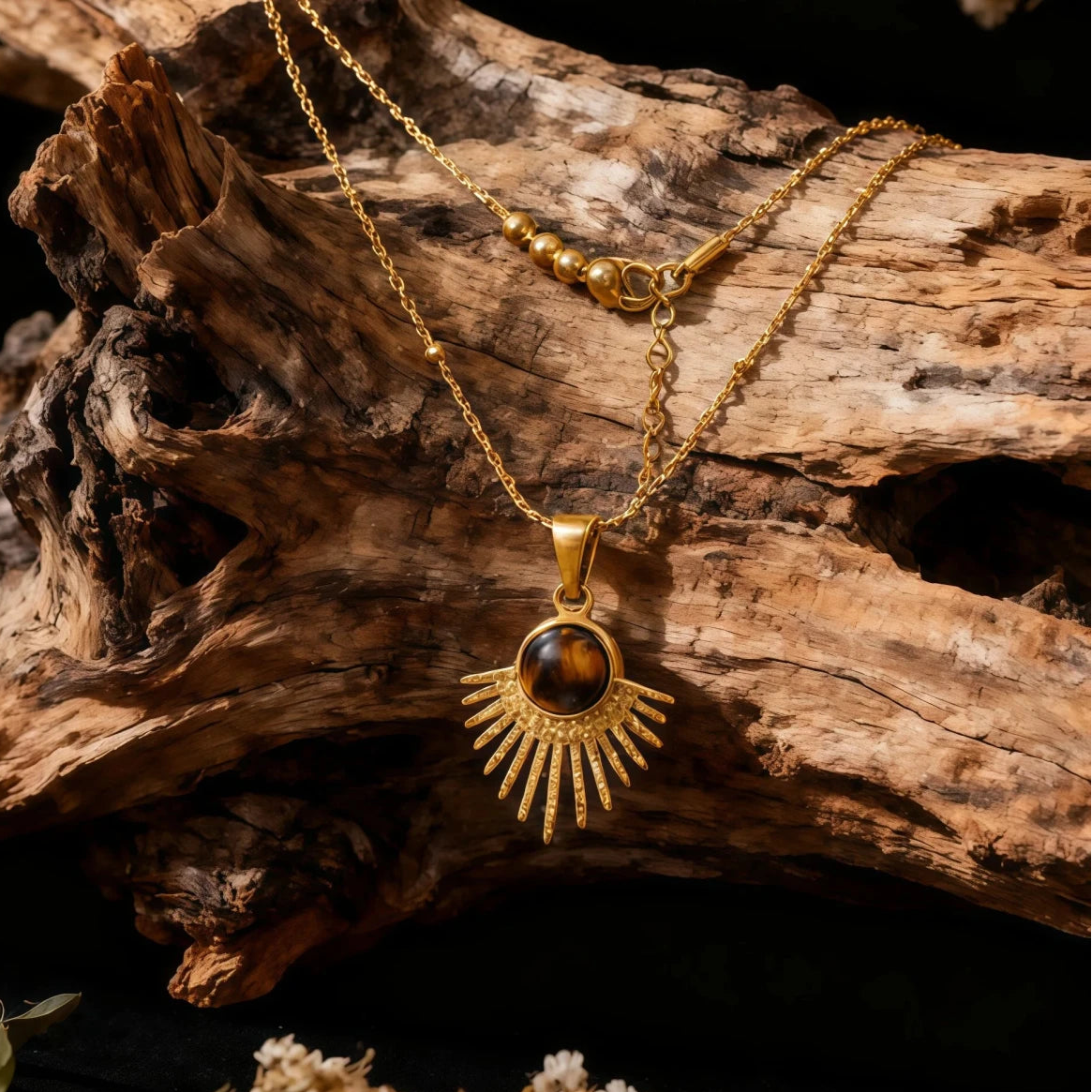 Macro shot of the gold sunburst pendant with a Tiger's Eye center and a light flare reflecting off the metal rays.