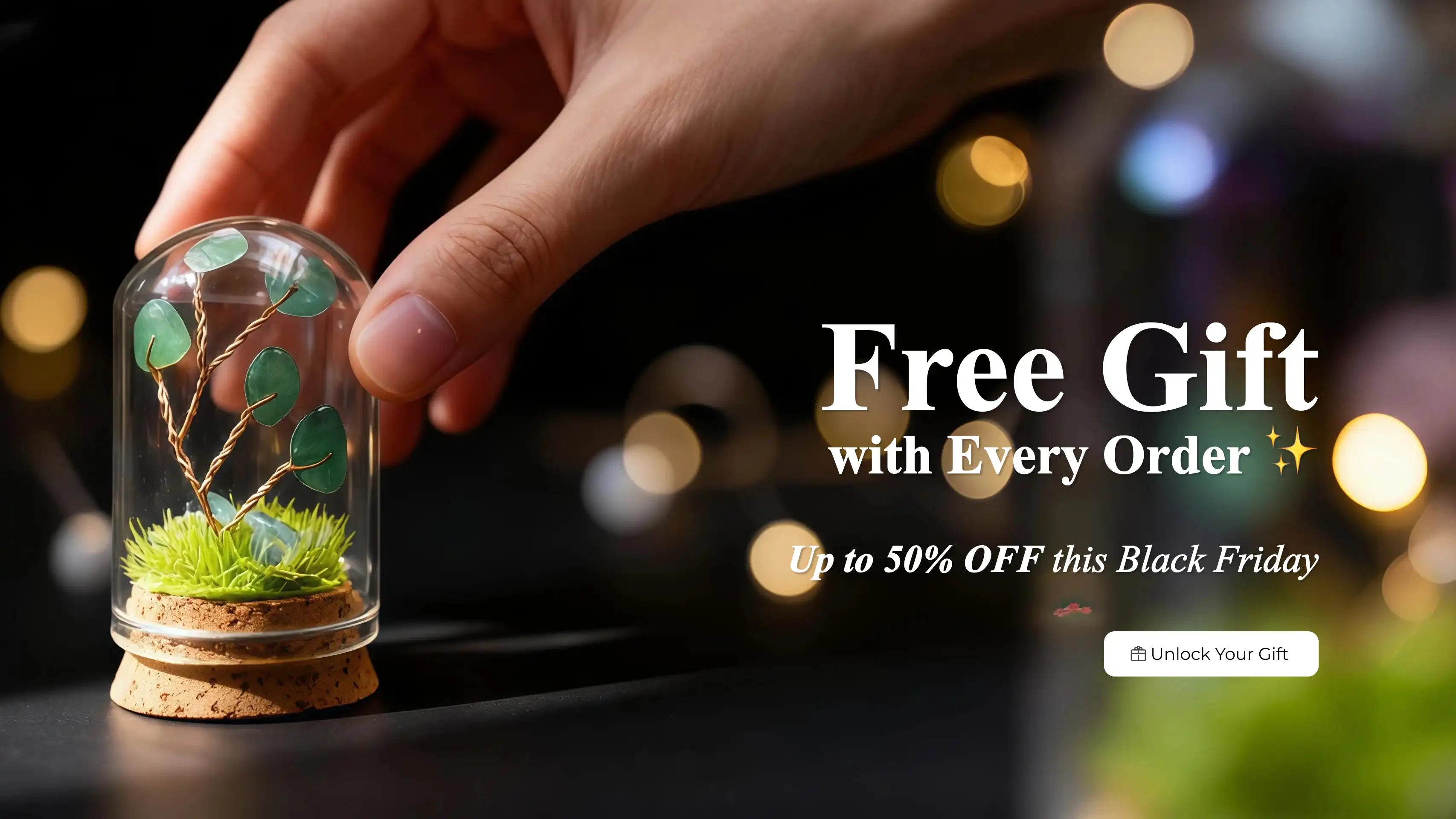 Hand holding a small glass dome with a crystal tree of life, blurred lights in the background, and promotional text for a free gift and Black Friday discount.
