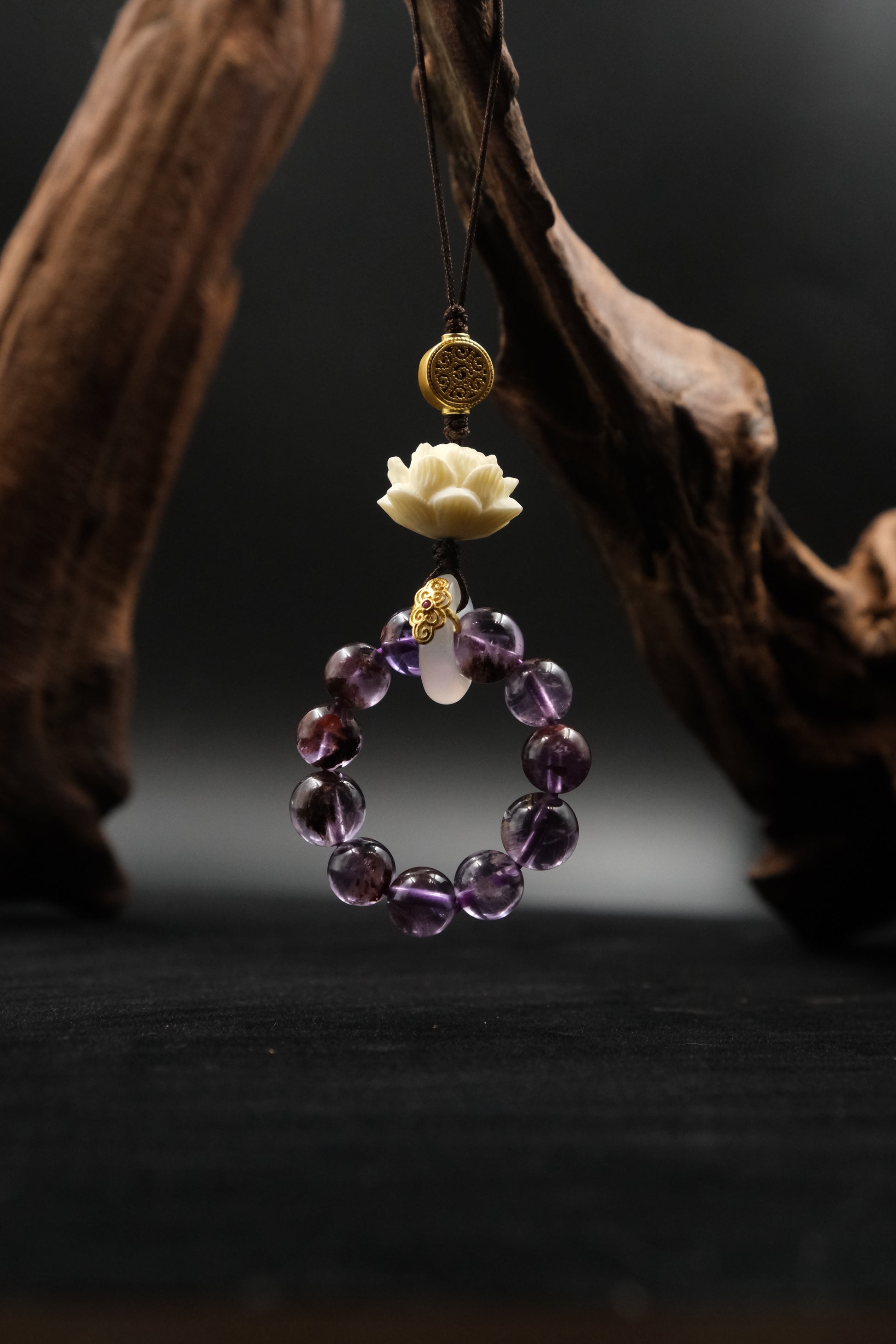 Bodhi Root for Mindfulness & Protection, Amethyst beaded necklace with gold accents and a white flower pendant on a dark background