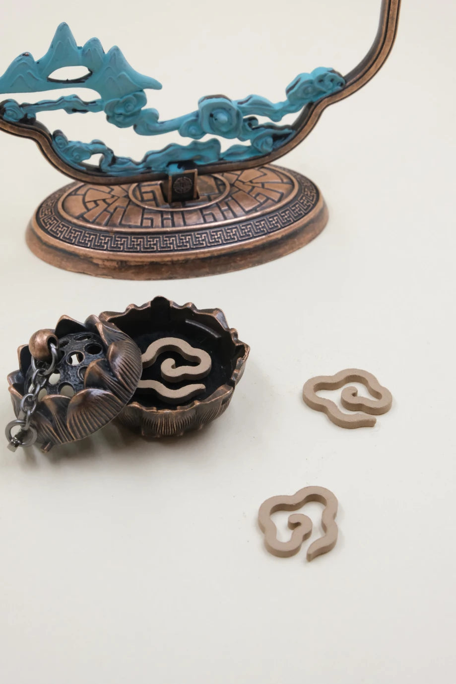 Feng Shui lotus-shaped hanging incense burner with a lotus bowl and cloud-shaped incense coils, set in a decorative frame featuring mountain and cloud details, symbolizing calm and positive energy.