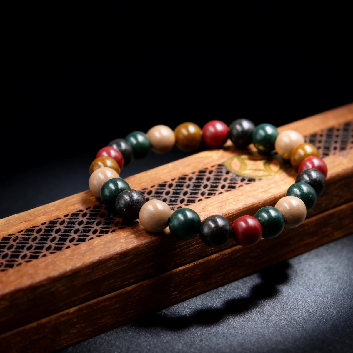 The five-element bracelet displayed on a carved wooden box.