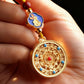 Gold pendant with intricate design held in a hand