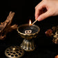 Hand lighting a match over an incense burner with a dark background
