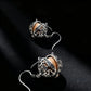 Pair of silver earrings with intricate designs on a black background