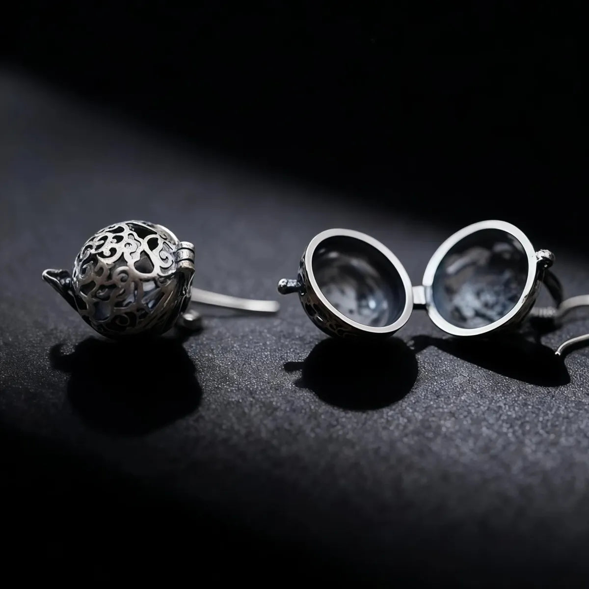 Silver spherical object and round eyeglasses on a dark surface