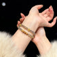 Close-up of hands wearing a erity_Gray_Agate_Sandalwood bracelet with a black background
