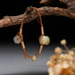 Pair of earrings with stone beads on a branch against a dark background