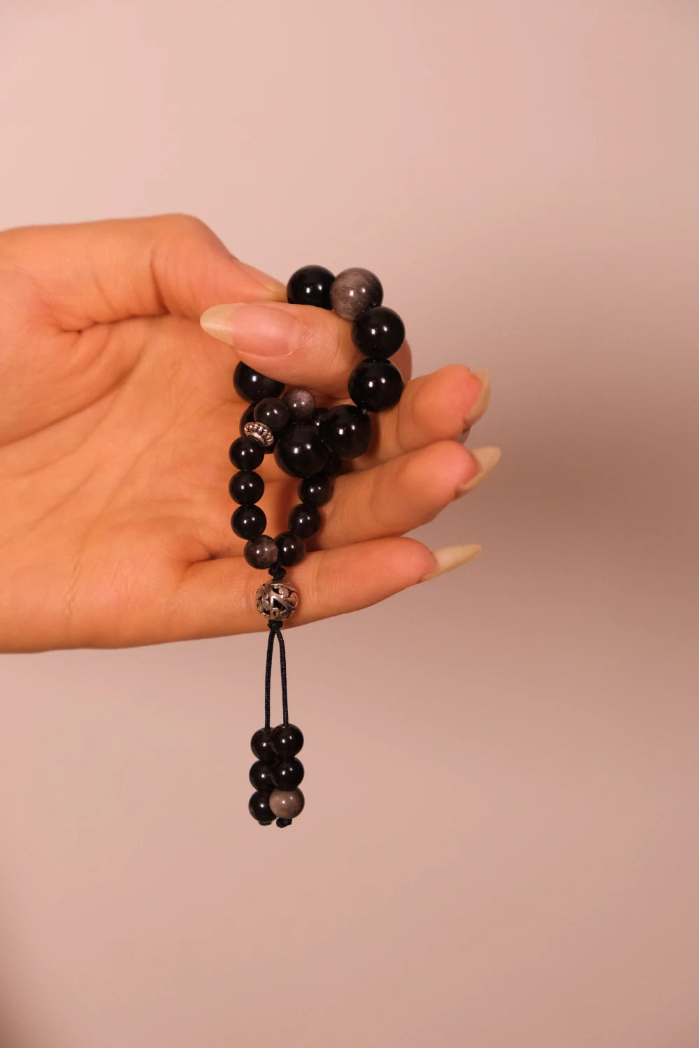 Hand holding Grounding & Protection – Tibetan Meditation Spinner against a beige background