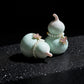 Two light blue ceramic gourds with pearl and butterfly decorations on a black background