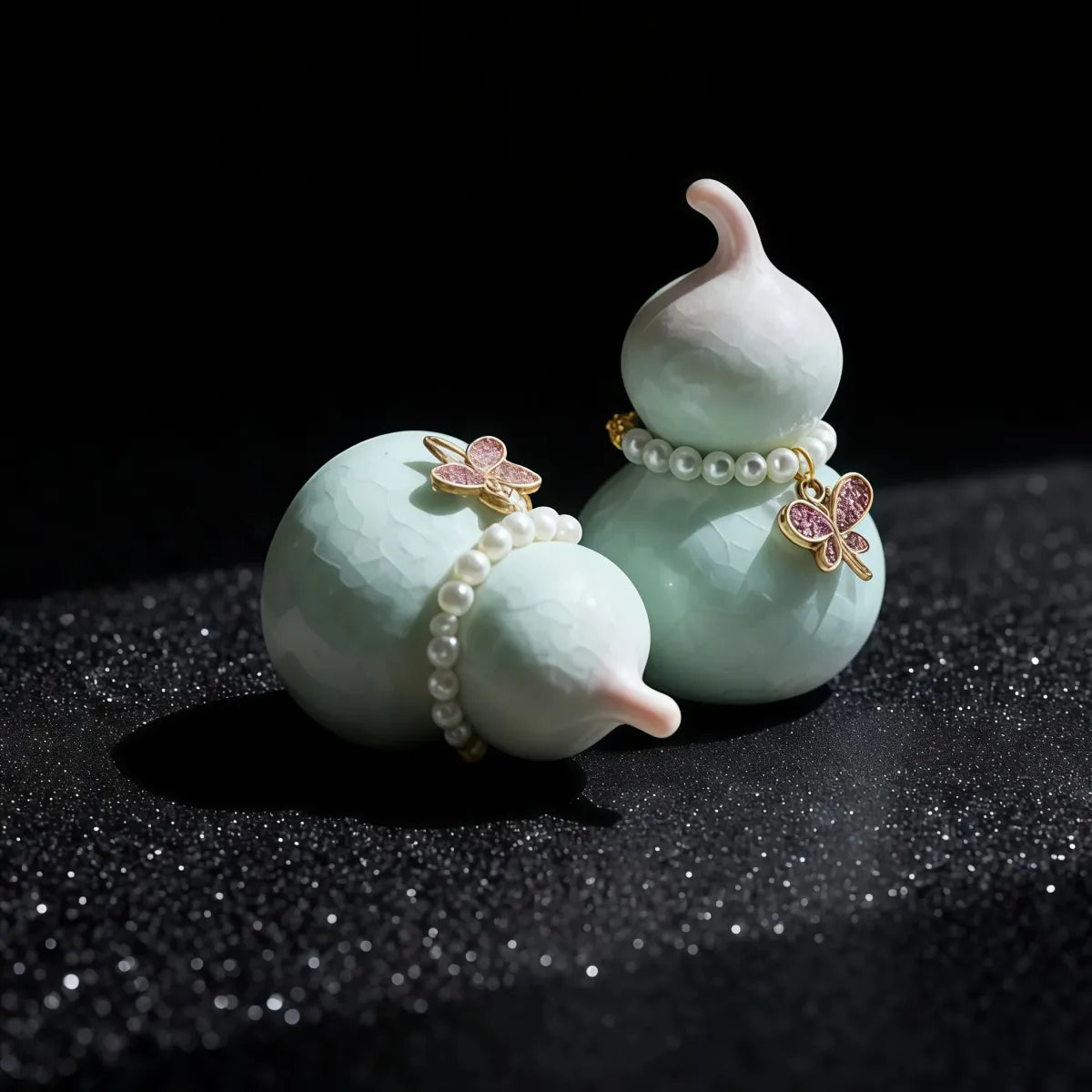 Two light blue ceramic gourds with pearl and butterfly decorations on a black background