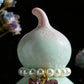 Decorative item with a light green gourd and pearl necklace on a dark background