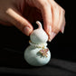 Decorative gourd with pearl and butterfly charm held by a hand on a black background