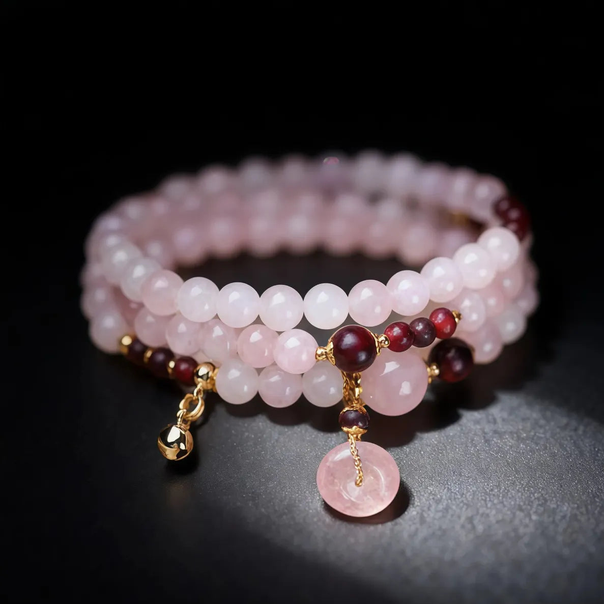Stack of pink beaded bracelets with gold and red accents on a dark background