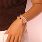 Close-up of a hand wearing multiple-circle Rose Quartz Amulet Bracelet on a plain background