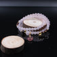 Rose Quartz Amulet Bracelet and a wooden slice on a black background
