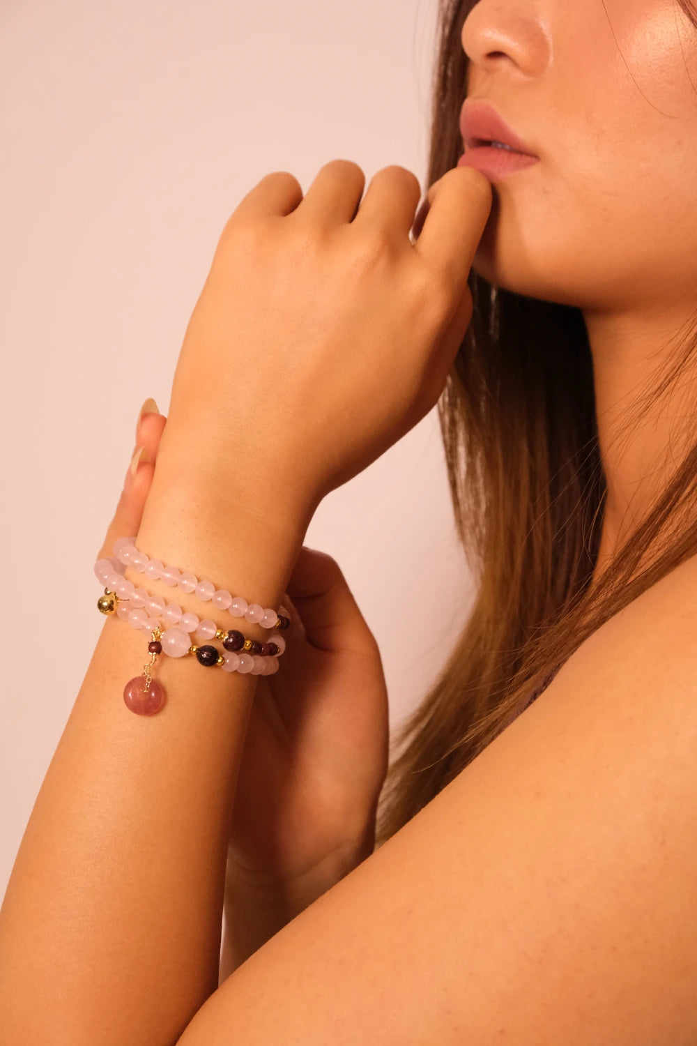 Close-up of a woman's arm wearing a Rose Quartz Amulet Bracelet against a neutral background